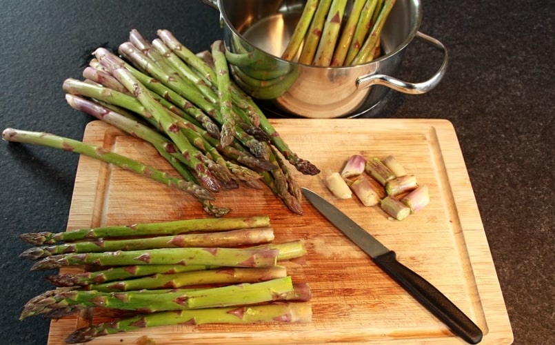 Chopping off the woody ends of asparagus on a wooden board