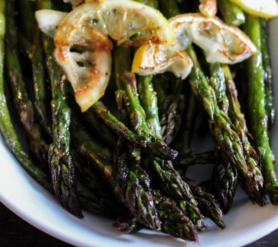 A bowl of grilled asparagus with lemon slices